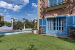 une cour avec une porte bleue et une pelouse dans l'établissement Casa Colonial Sitges Hills, à Olivella