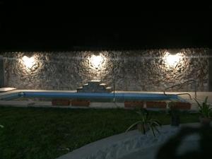 una piscina con luci su un muro di pietra di notte di Hostal Candelaria a Cafayate