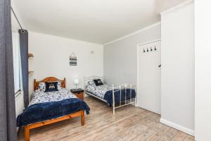 two beds in a bedroom with white walls and wood floors at Merriesands, Middleton - On - Sea in Middleton-on-Sea