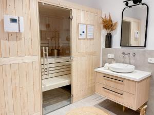 a bathroom with a sink and a shower with a mirror at My Baltic Sea - Ferienwohnungen im Seaside House in Scharbeutz