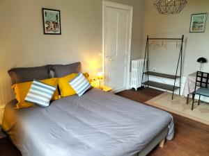 1 dormitorio con 1 cama grande con almohadas amarillas en Tours - Rochebonne (chambre à louer), en Tours
