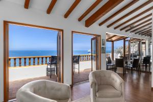 een woonkamer met stoelen en een balkon met uitzicht op de oceaan bij Premium Ocean Corner Unit, Fireplace, Golf Cart, 21 Steps from Top in Avalon