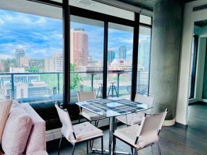 einen Tisch und Stühle in einem Zimmer mit einem großen Fenster in der Unterkunft LUXURY DT, 2 Bedroom DEAL, Private Balcony, Full Kitchen, Gym - FREE PARKING in Calgary