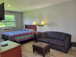 a living room with a couch and a bed and a chair at Knights Inn Cobourg in Cobourg