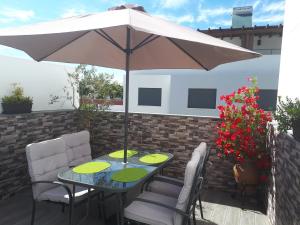 Una mesa y sillas con una sombrilla en un patio. en MAR I TERRA, en Olhão