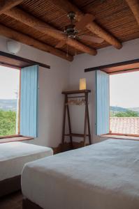 1 dormitorio con 2 camas y 2 ventanas en Casa Guatí, en Barichara