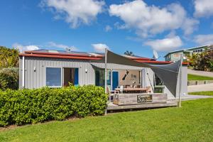 a small house with a tent and a table at Hahei Beach Bach. in Hahei