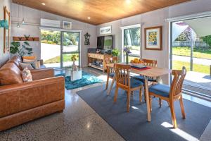 a living room with a table and a couch at Hahei Beach Bach. in Hahei