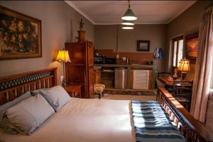 a bedroom with a large bed and a kitchen at Koekeloer Selfcatering Cottages in Nieu-Bethesda