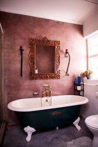 a bath tub in a bathroom with a mirror at Koekeloer Selfcatering Cottages in Nieu-Bethesda