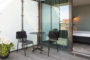 2 Stühle und ein Tisch auf einem Balkon mit einem Bett in der Unterkunft Scandic Helsfyr in Oslo