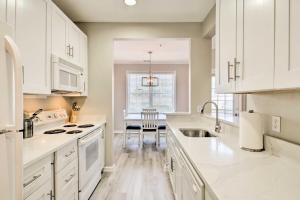 a kitchen with white cabinets and a sink and a table at Rehoboth Beach Condo with Patio 5 Mi to Ocean! in Rehoboth Beach