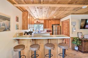 a kitchen with wooden cabinets and a counter with stools at Peaceful Big Bear Cabin Walk to Lake Access! in Big Bear Lake