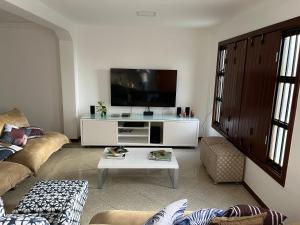 a living room with a couch and a tv at Casa beira mar cond fechado farol Itapuã in Salvador