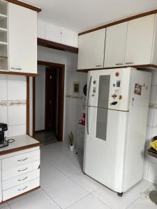 a kitchen with white cabinets and a white refrigerator at Casa beira mar cond fechado farol Itapuã in Salvador