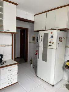 eine Küche mit weißen Schränken und einem weißen Kühlschrank in der Unterkunft Casa beira mar cond fechado farol Itapuã in Salvador