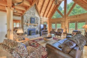 a living room with a stone fireplace in a log cabin at Gorgeous Piney Creek Cabin with River Access! in Piney Creek