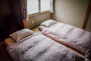 dos camas sentadas una al lado de la otra en un dormitorio en Vacation House ROMAN, en Noboribetsu