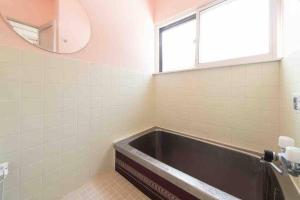 a bathroom with a bath tub and a mirror at Vacation House ROMAN in Noboribetsu