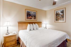 una camera da letto con un letto bianco con due comodini e due lampade di Grand Lodge 369 a Crested Butte