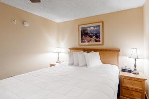 una camera da letto con un grande letto bianco con due lampade di Grand Lodge 369 a Crested Butte