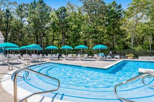 una piscina con sombrillas y sillas azules en Sea Colony - 56053 Pinewood Dr, en Bethany Beach