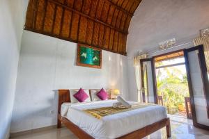 a bedroom with a bed with pink pillows at The Mountain Cottage in Nusa Penida