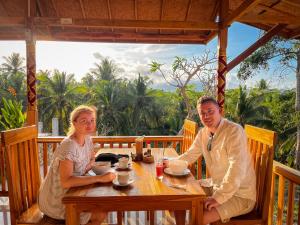 a man and a woman sitting at a table at Griyatama Bungalow in Nusa Penida