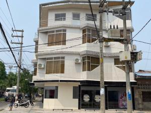 a tall white building with a motorcycle parked in front of it at Alojamiento Everglow in Iquitos