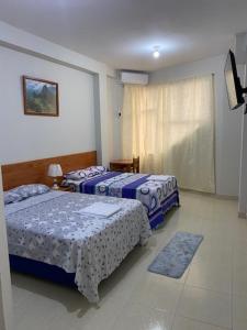 1 dormitorio con 2 camas y ventana en Alojamiento Everglow, en Iquitos