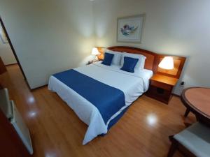 a bedroom with a large bed with blue pillows at Summit Suítes Hotel Jundiaí in Jundiaí