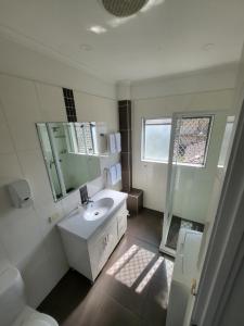 a white bathroom with a sink and a mirror at Central Motel Mooloolaba in Mooloolaba