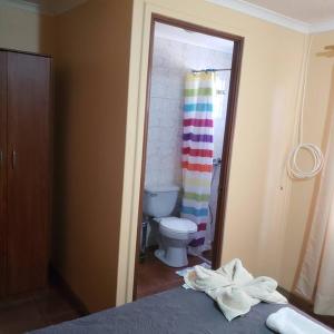 a bathroom with a toilet and a rainbow shower curtain at CASA VICTORIA in San Pedro de Atacama