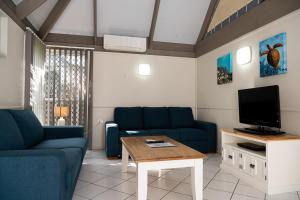 a living room with blue couches and a tv at Kellys Beach Resort in Bargara