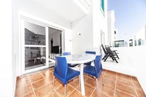 a dining room with a table and blue chairs at Luxury Beach Apartment Nasa in Playa Honda