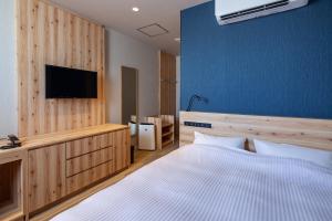 a bedroom with a bed and a tv on a wall at Y's CABIN&HOTEL Naha Kokusai Street in Naha