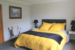 um quarto com uma cama grande e um cobertor amarelo em Rosies Place em Oamaru