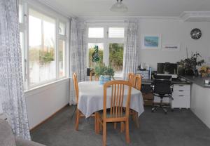 a dining room with a table and chairs and a desk at Rosies Place in Oamaru