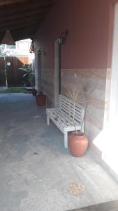 a white bench sitting next to a building with a potted plant at Chalés sal da terra/Chalé in Caraguatatuba