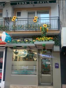 a store front with a balcony with flowers on it at Hostal Boutique Luna de Gavín in Cullera