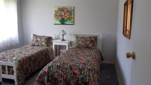 - une chambre avec des lits jumeaux et une chaise dans l'établissement Butterfly Cottage, à Tumut