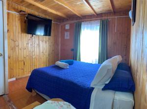 a bedroom with a blue bed and a television at Lefun & Lafquen de Pichilemu in Pichilemu
