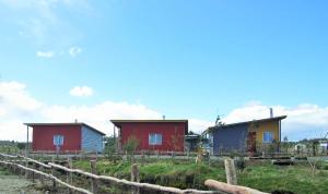 een rij huizen in een veld naast een hek bij Cabañas Juan José in Castro