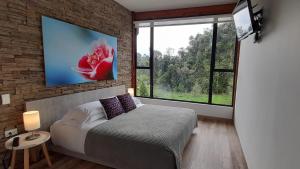a bedroom with a bed and a large window at Hotel Termales Tierra Viva in Manizales