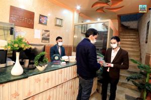 three men wearing face masks standing at a counter at Royal INN Guest House in Lahore