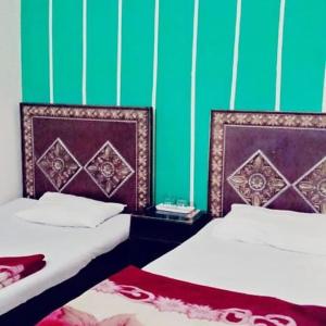 two beds in a room with green and purple at Royal INN Guest House in Lahore