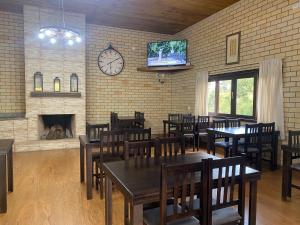 a dining room with tables and chairs and a clock at Pousada Rural Encanto do Riacho in Bom Jardim da Serra