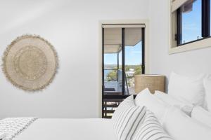 a white bedroom with a bed and a window at Wanda Point House - pure tranquillity and walk to beach in Salamander Bay