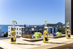 a table with three bottles of beer and a plate of food at Penthouse Palace - Luxurious Harbourview Location in Nelson Bay