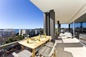 a patio with a wooden table and chairs on a balcony at Penthouse Palace - Luxurious Harbourview Location in Nelson Bay